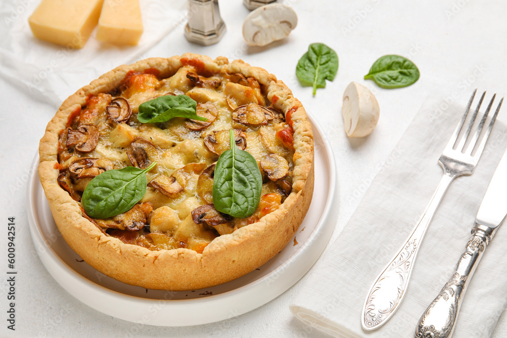 Mushroom pie with spinach leaves and cutlery on white background