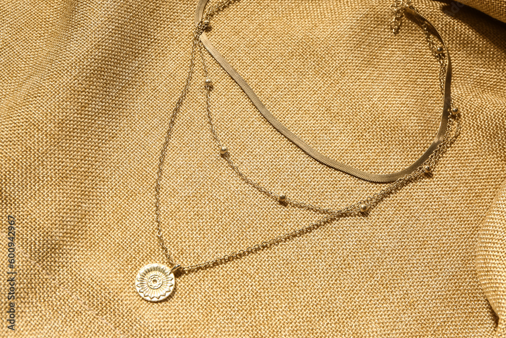 Beautiful chain necklace on beige fabric background