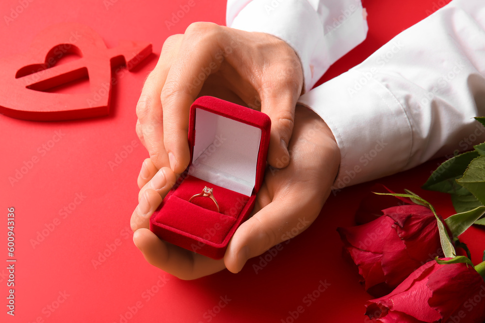 Man with engagement ring, roses and heart on red background