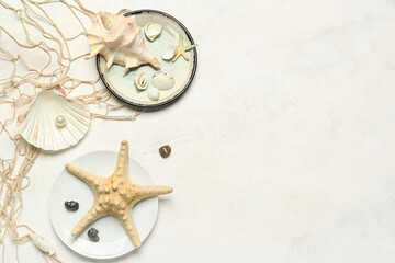 Wall Mural - Plates with seashells, starfish and net on light background