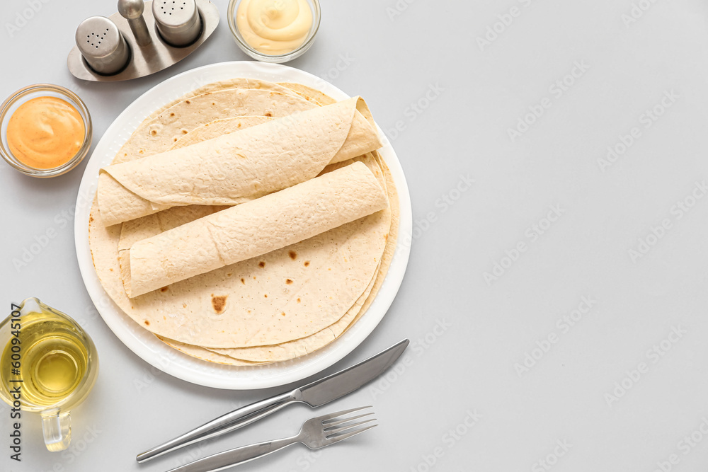 Plate of thin lavash with oil and sauces on grey background