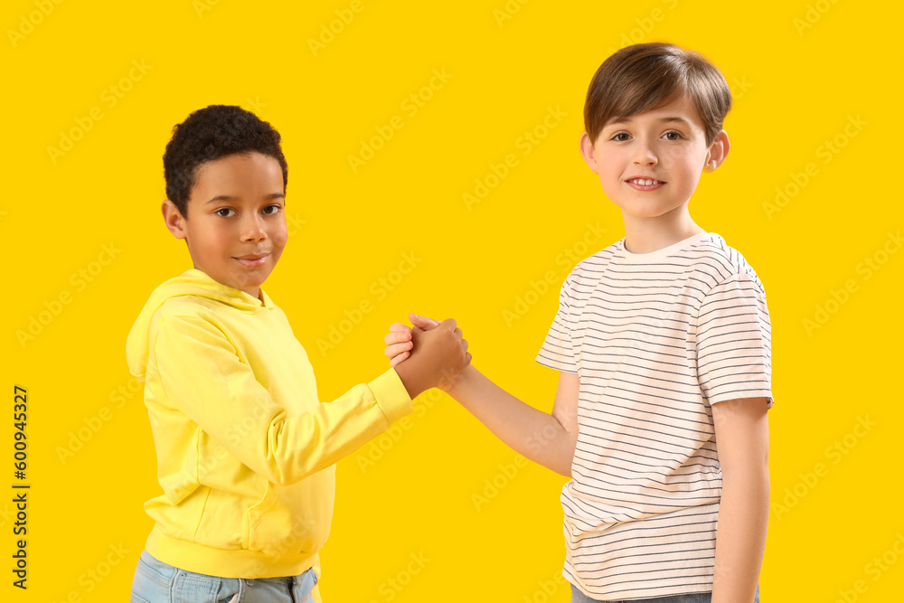 Little boys holding hands on yellow background. Children's Day celebration