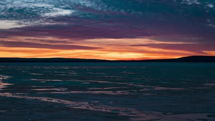 Wall Mural - Dramatic sunset timelapse at an icy lake, sunlight colors reflecting on clouds