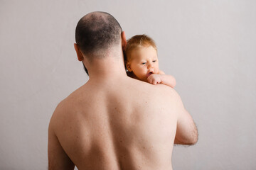 Father holds tiny little baby while he looks over his shoulder