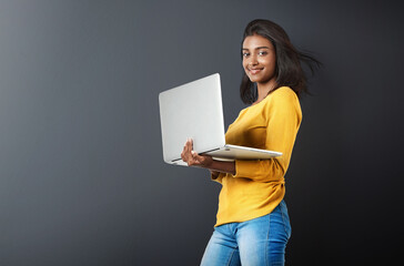 Wall Mural - Laptop, portrait and woman typing online, internet or web email isolated in a studio grey background feeling happy. Mockup, social media and female student or person working and using technology