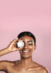 Wall Mural - Smile, skincare and woman with cream container in studio isolated on pink background mockup space. Eyes closed, creme cosmetics and Indian female model with lotion, moisturizer product or dermatology