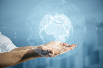 Poster - Close up of male hands holding glowing polygonal globe on blurry city background. World map and earth concept.