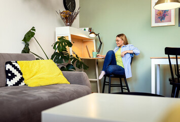 Smiling woman programmer tworking remotely using laptop from the comfort of her home.