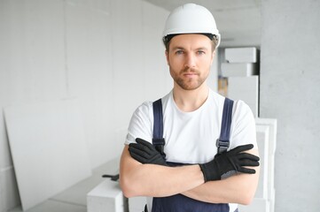 Wall Mural - Portrait of positive, handsome young male builder in hard hat.