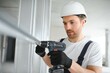 © Serhii - drywall worker works on building site in a house.