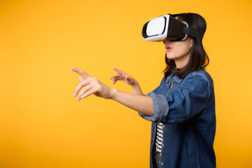 Poster - Young asian woman get experienced wearing virtual reality headset game entertainment isolated on yellow background. Winner of cyber future video game concept.
