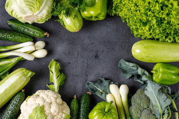 Wall Mural - Frame of green raw vegetables on black background. Top view of healthy organic food. Copy space