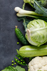 Wall Mural - Border of organic green raw vegetables on black table. Top view of healthy organic food. Copy space