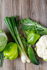 Wall Mural - Green raw vegetables on wooden background. Healthy organic food.