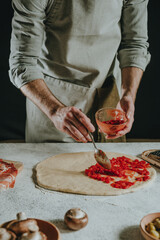 Wall Mural - Man preparing pizza on a white table against black background