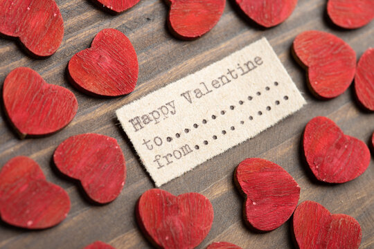 Happy Valentine- typed text. Valentines Day greetings concept. Little red wooden hearts close up. Valentines greeting card.