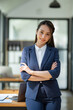 © crizzystudio - Attractive asian businesswoman standing with crossed arms and looking at camera in office confident and happy with business success