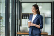 © crizzystudio - Beautiful and confident Asian businesswoman holding a cup of coffee to drink during break Relax with your own business happily in the office.