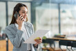 © crizzystudio - Attractive Asian businesswoman standing on the phone talking about real estate projects and chatting with happy smiles at the office.