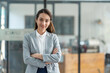 © crizzystudio - Attractive asian businesswoman standing with crossed arms and looking at camera in office confident and happy with business success