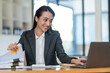 © crizzystudio - Asian businesswoman clicking details on laptop computer analyzing data checking accuracy of financial income happily in office management concept management.