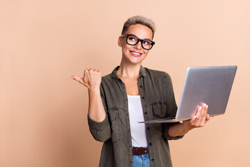 Photo of young thinking business hr manager woman short hairdo point finger hold laptop empty space isolated on beige color background