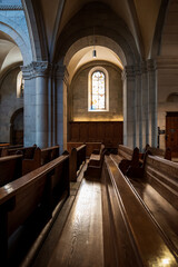 Sunlight beaming down on empty wooden church pews. Wide angle view, no people