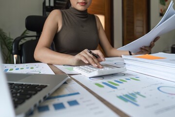 Wall Mural - young woman calculating domestic expenses in financial paperwork indoors, focused lady managing monthly banking payments summarizing utility bills and taxes at home