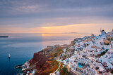 Fototapeta Uliczki - Famous greek iconic selfie spot tourist destination Oia village with traditional white houses and windmills in Santorini island on sunset in twilight, Greece