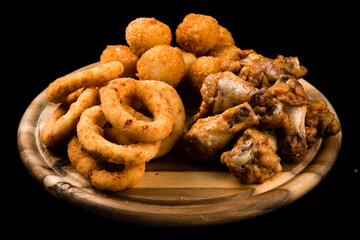 Wall Mural - Snack fried chicken legs, breaded mozzarella cheese balls and crispy squid rings breaded (caramari) on dark background.