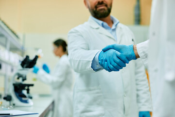 Wall Mural - close up of scientists shaking hands while working in laboratory.