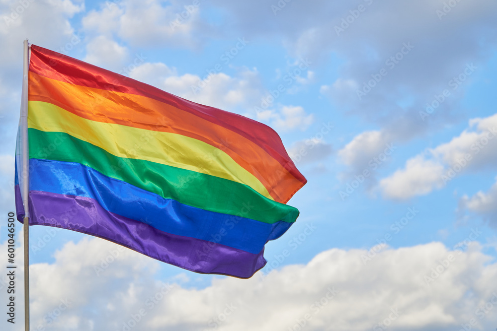 LGBTQ pride flag waving on blue sky with clouds Stock Photo | Adobe Stock