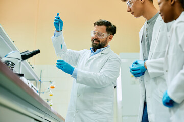 Happy science teacher and his students during an experiment in laboratory.