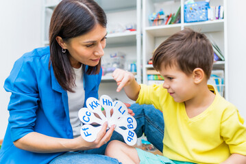 A cute boy with a speech therapist is taught to pronounce the letters, words and sounds.