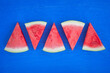 slices of watermelon in triangular shapes on a bright blue wooden surface