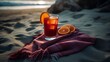 Cocktail with oranges on a towel at the beach