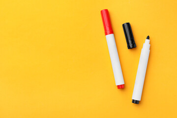 Bright color markers on orange background, flat lay. Space for text