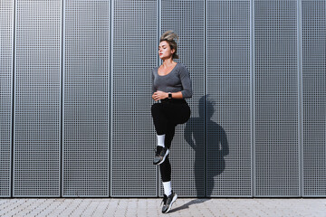 Wall Mural - Woman athlete running in place during her high-intensity interval training on the street