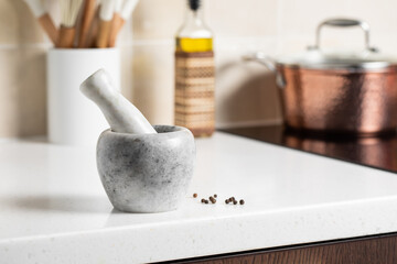 Marble mortar with pestle. Stylish bright kitchen in the background.