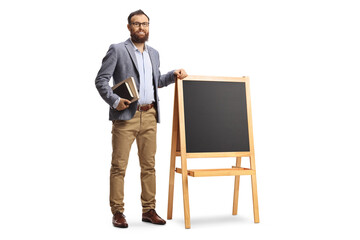 Canvas Print - Full length portrait of a bearded male teacher standing next to a blackboard with books in his hands