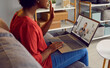 © Studio Romantic - African American woman sitting on sofa at home, looking at laptop computer screen, and greeting her psychotherapist at video conference meeting session. Remote psychotherapy, online therapy concept