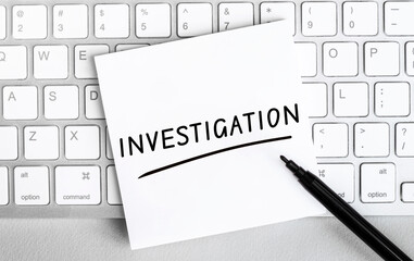 Poster - white paper with text investigation lying on the keyboard