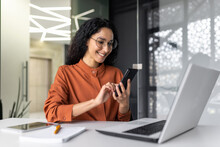 Beautiful Woman In The Office, Happy And Smiling Latin American Business Woman Uses Internet Phone Close Up, Female Worker Reads Message And Browses Internet Pages Inside Office Building