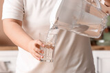Fototapeta Kawa jest smaczna - Woman pouring water from filter jug into glass