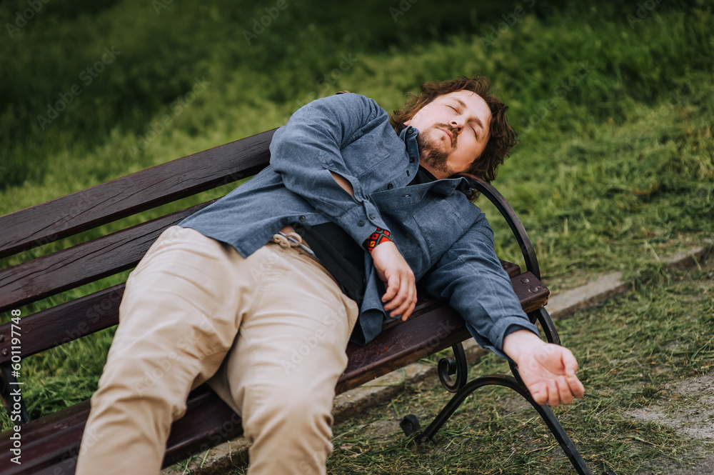 Drunk adult unhappy man, drunkard, alcoholic sleeps in the park ...