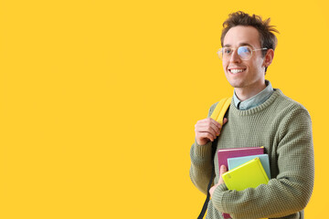 Wall Mural - Male student with notebooks on yellow background