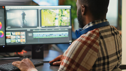 Poster - Young graphic designer artist editing video content on software, using focus lighting and color grading. Male filmmaker working on movie montage edit on pc multi monitors, cinematographer.