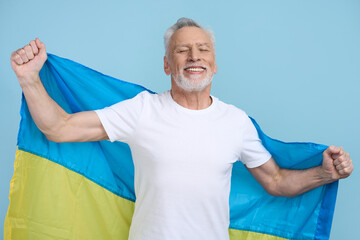 Happy smiling senior man carrying Ukrainian blue yellow flag. Patriotism. Independence Day concept