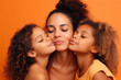 © Loks - Multiracial mid woman and children hugging on an orange background