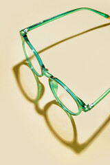 Stylish green eyeglasses on pale yellow background